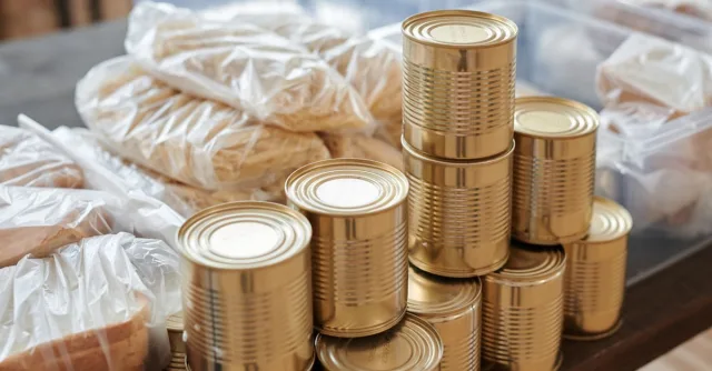 A stack of canned goods and packaged foods on a table, perfect for donation drives.