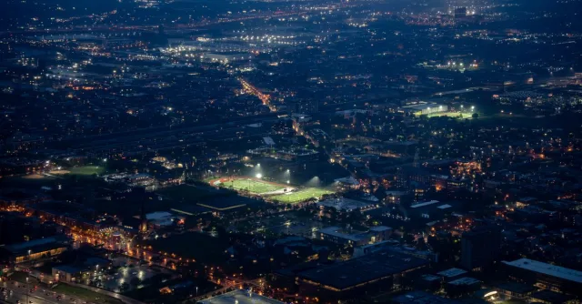 Aerial night view of a vast city with illuminated streets, highlighting urban life.