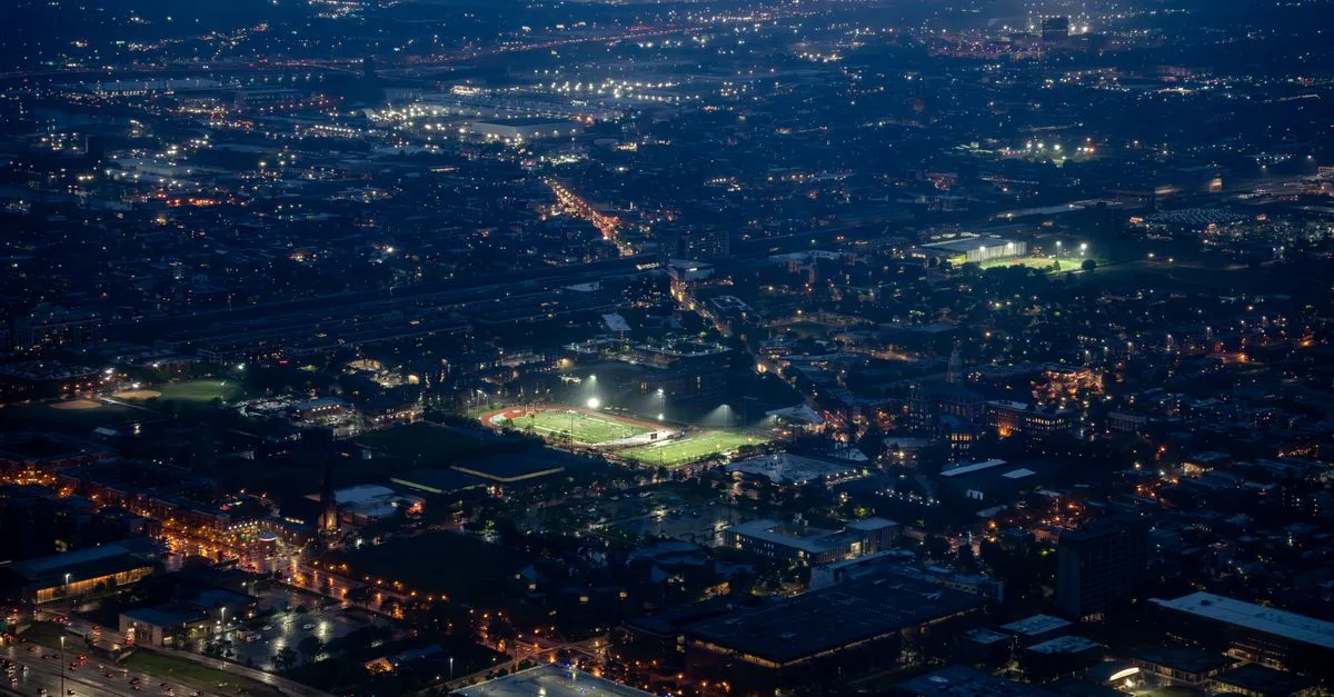 Aerial night view of a vast city with illuminated streets, highlighting urban life.