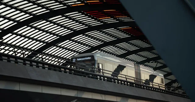 Train at Amsterdam Central Station under the modern, geometric roof structure.
