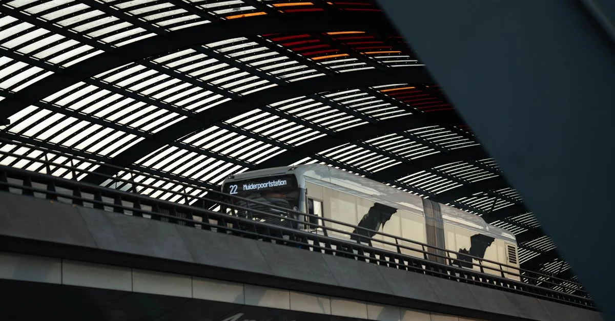 Train at Amsterdam Central Station under the modern, geometric roof structure.