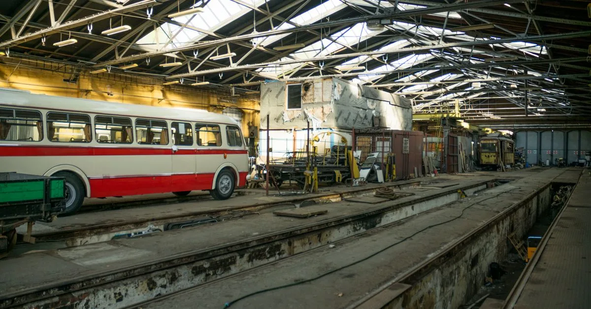 Inside view of an urban transit depot in Wrocław with buses and tram undergoing maintenance.
