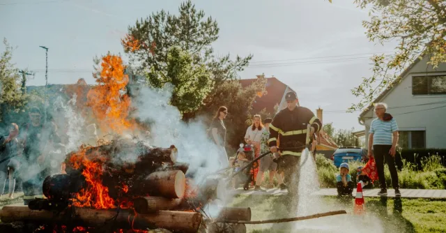 Firefighter putting out a controlled fire during a training demonstration in a residential area.