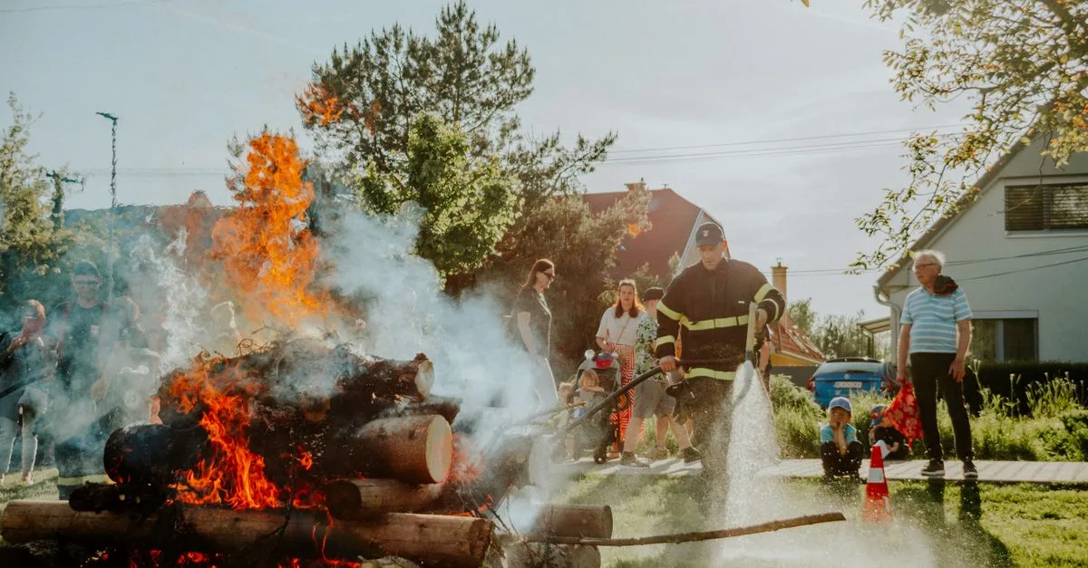 Firefighter putting out a controlled fire during a training demonstration in a residential area.