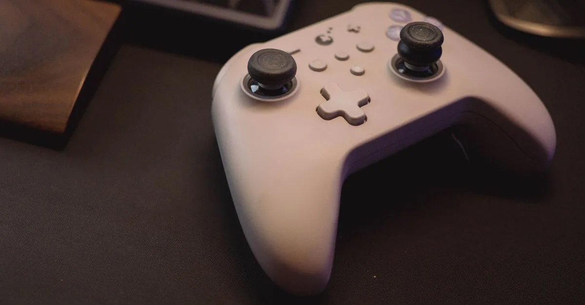 White gaming controller on a black desk setup, symbolizing modern gaming.