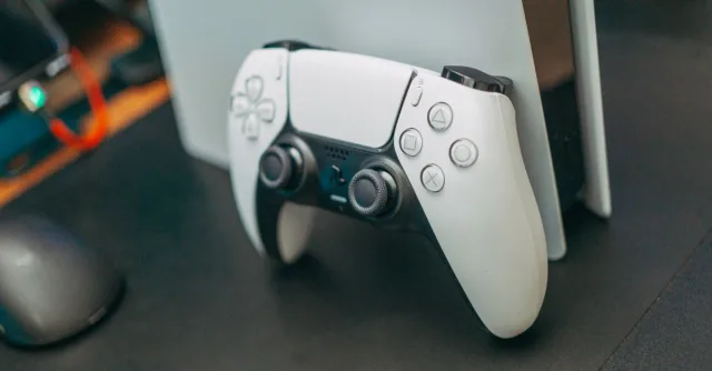Close-up of a PlayStation 5 controller resting on its console, showcasing modern gaming technology.