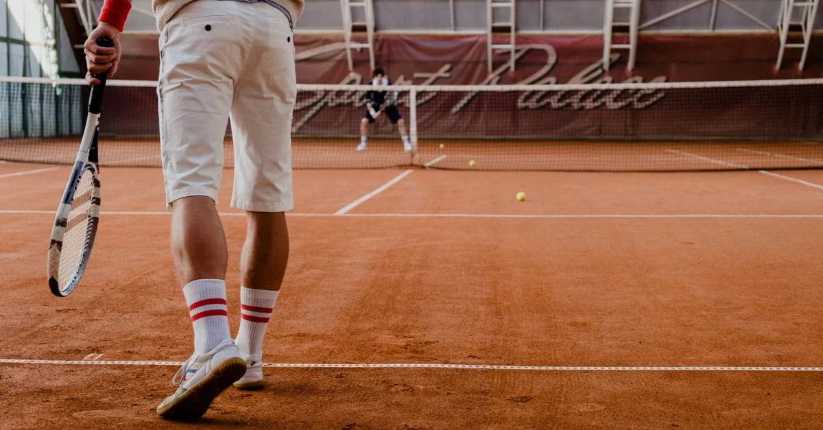 Players competing in a tennis match on an indoor clay court.
