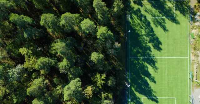 Aerial view of a lush forest beside a soccer field in Jönköping, Sweden.