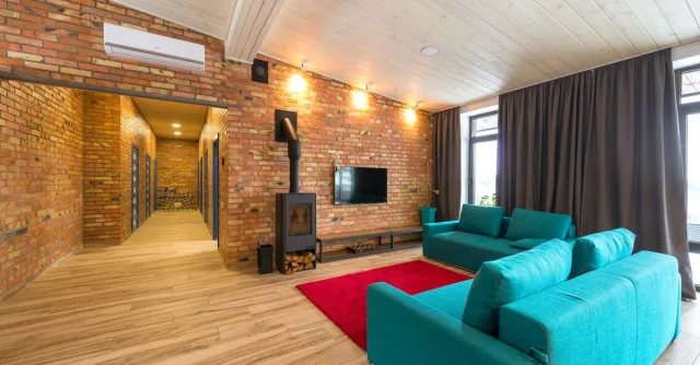 Spacious living room with blue sofas, red rug, and brick walls. Cozy and contemporary interior.