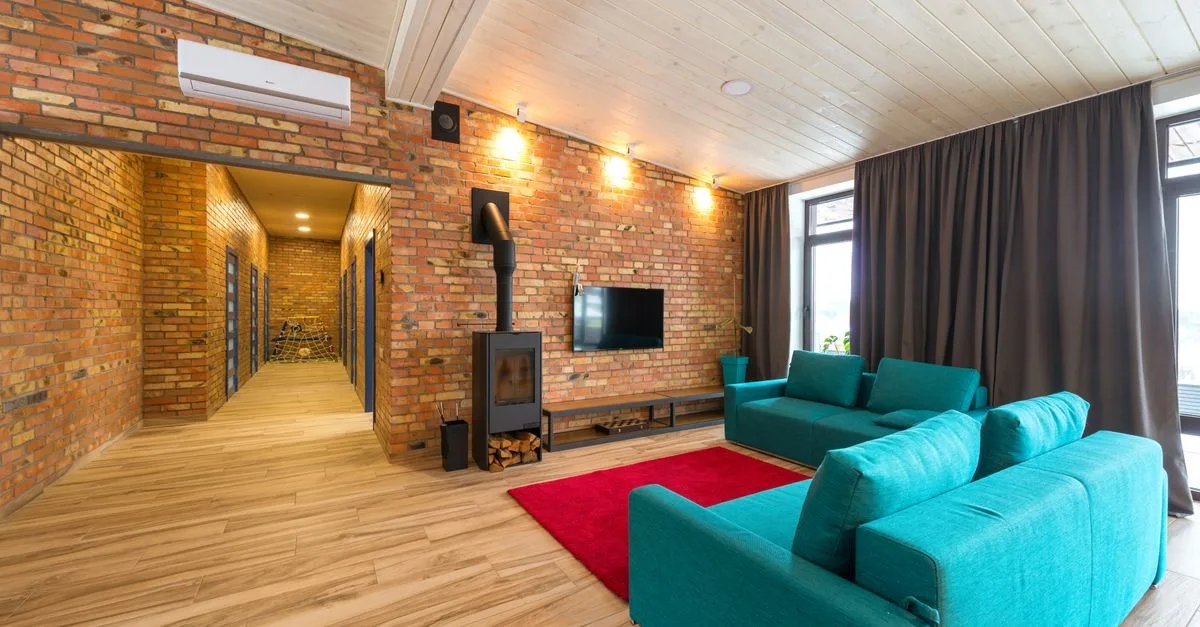 Spacious living room with blue sofas, red rug, and brick walls. Cozy and contemporary interior.
