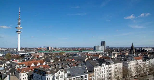 A stunning aerial view of Hamburg's skyline featuring the iconic Fernsehturm under a clear blue sky.