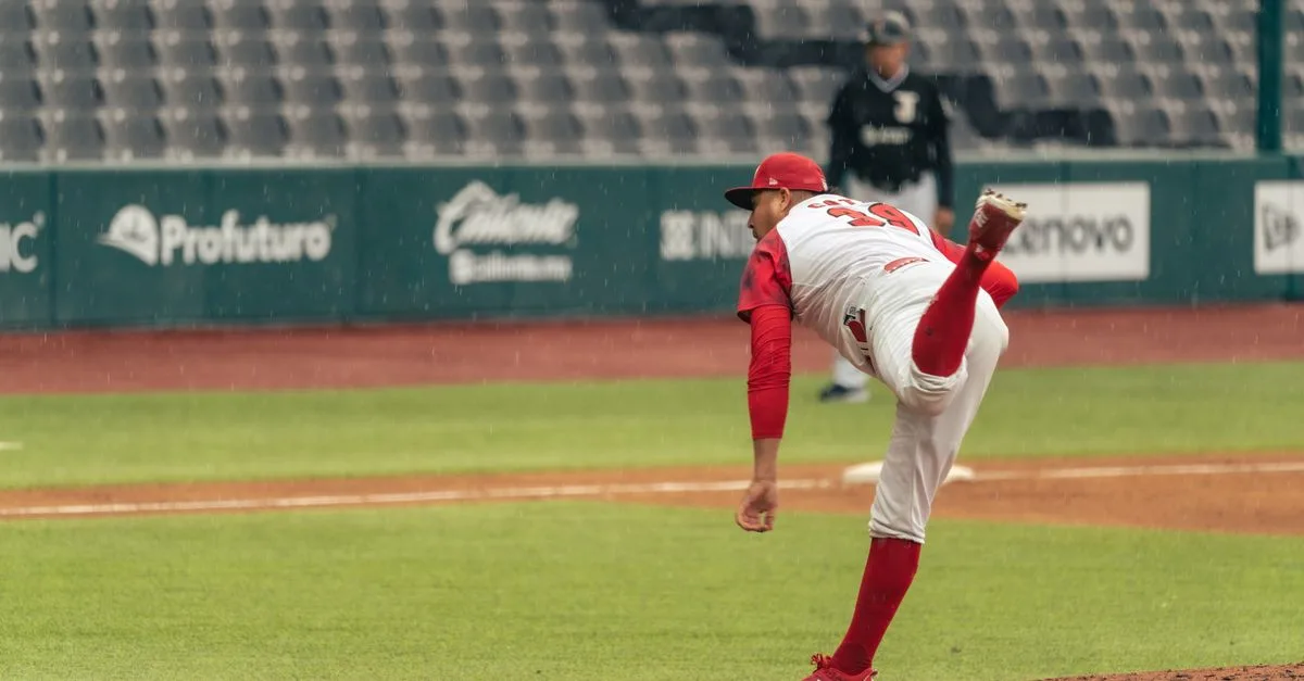 A baseball pitcher throws a pitch in a rainy stadium during a game.
