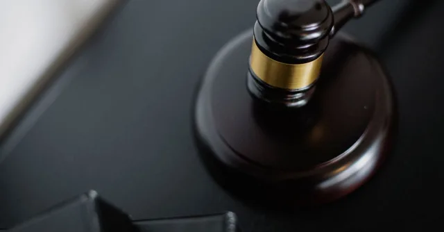 From above of wooden gavel on round surface near folders on table in courtroom
