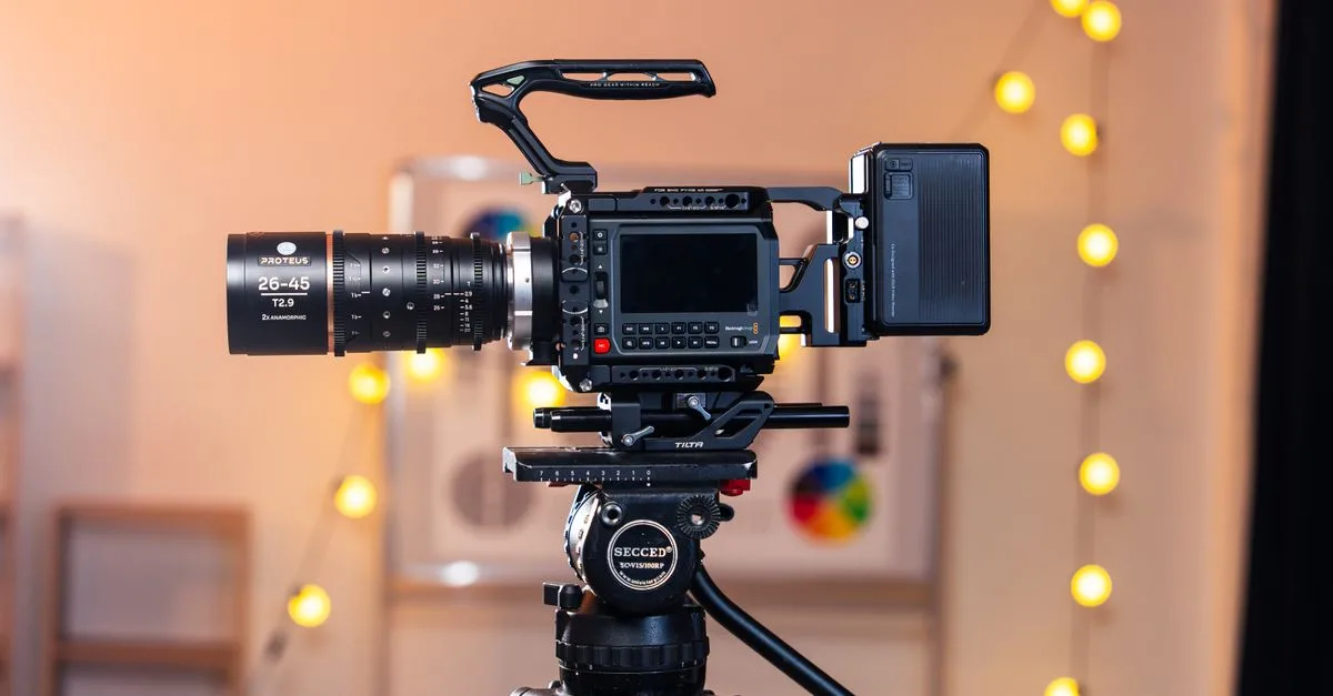 A high-quality video camera mounted on a tripod in a warmly lit studio setting with bokeh lights.