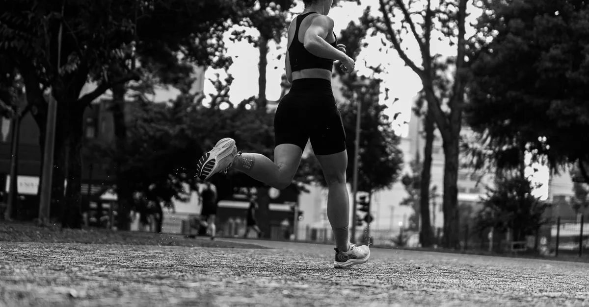 Dramatic black and white photo of a woman running through a park.