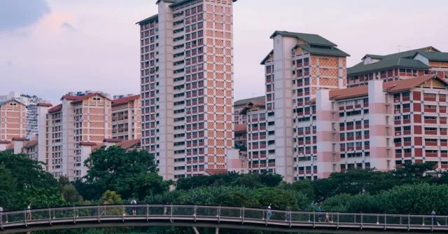 A view of Singapore's high-rise apartments with a pedestrian bridge and greenery.
