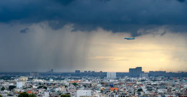 Dramatic view of a plane flying over a city during a storm with heavy clouds and rain.