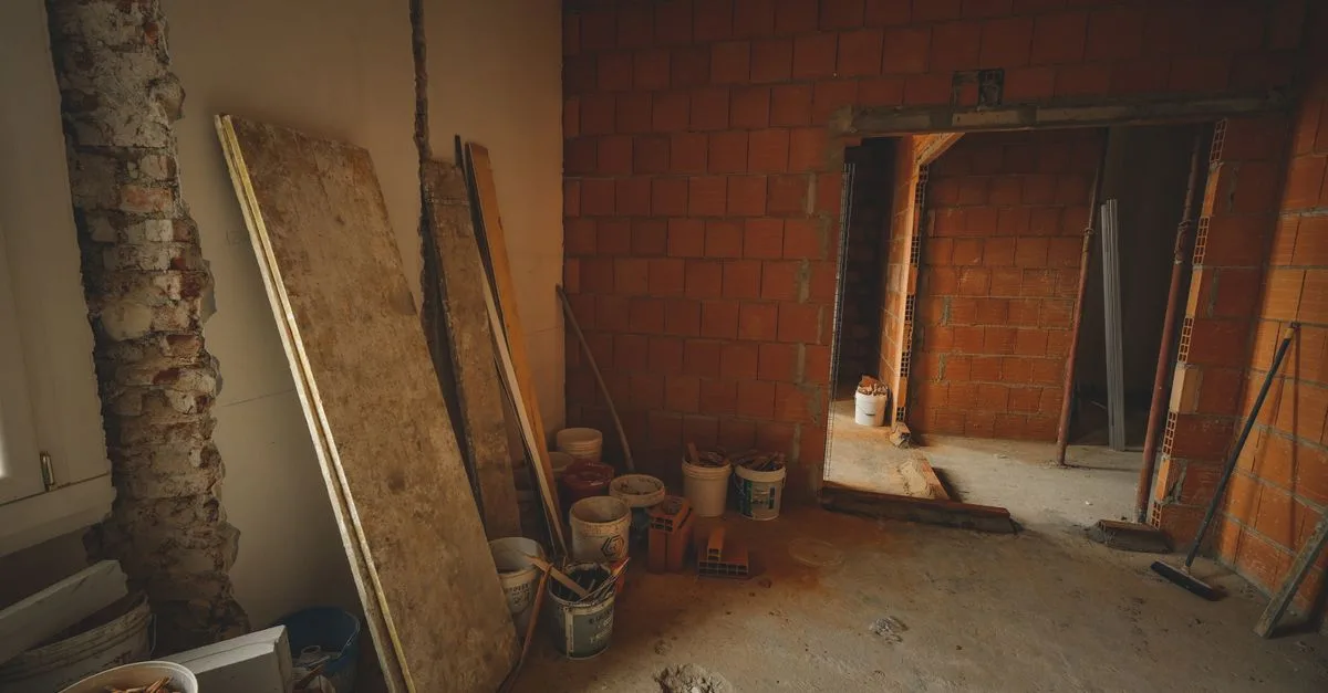 A red brick wall under construction with tools and materials scattered around in a renovation project.
