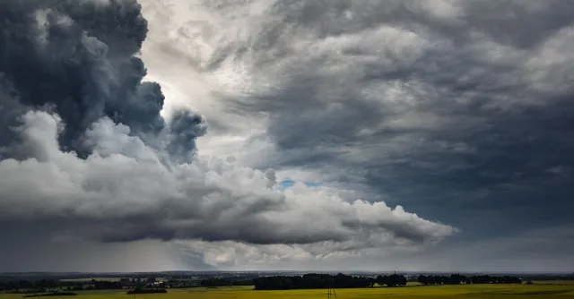 Dark storm clouds loom over the green fields of Poland, capturing nature's power.