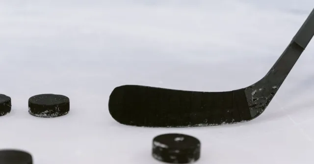 Detailed view of a hockey stick and pucks on ice, perfect for sports visuals.