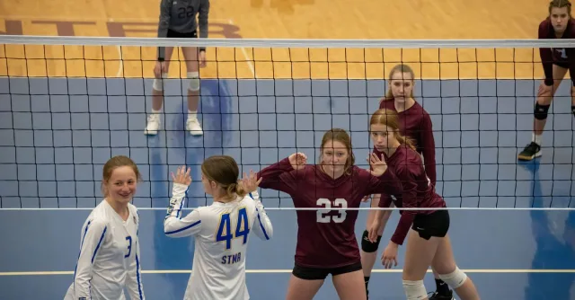 Teen girls playing volleyball indoors in Rochester, MN, showcasing teamwork and competition.