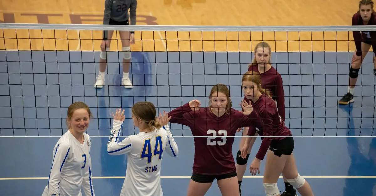 Teen girls playing volleyball indoors in Rochester, MN, showcasing teamwork and competition.