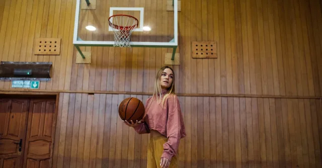 Woman holding a basketball on an indoor court, ready for the game.