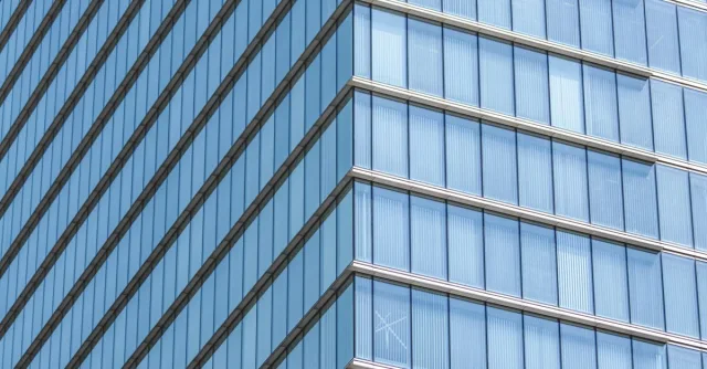 Close-up of a modern glass building facade showcasing geometric lines and reflections.