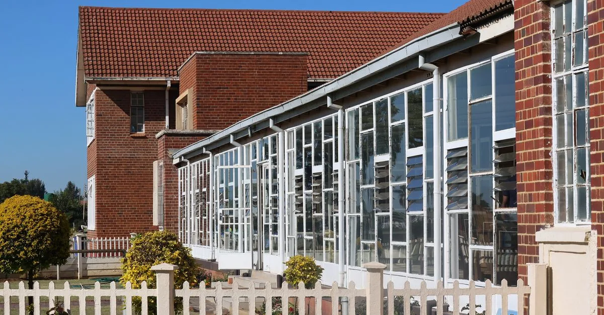 Exterior view of a modern brick building with extensive glass windows and red roof.