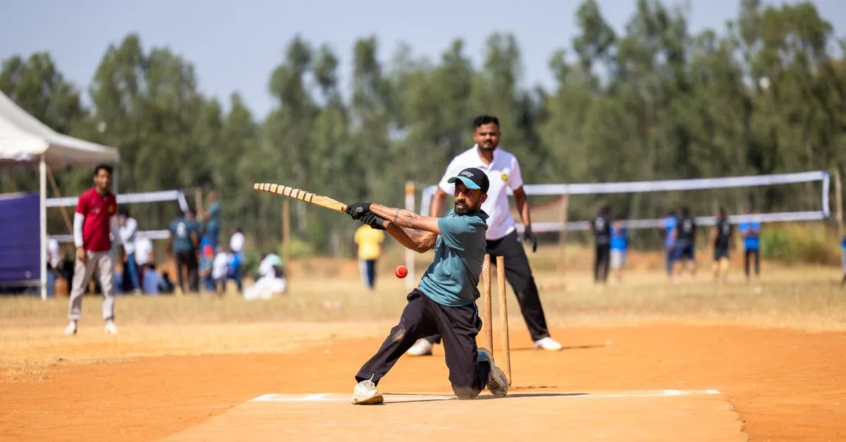 Cricket player skillfully hitting a ball during a lively outdoor match on a sunny day.