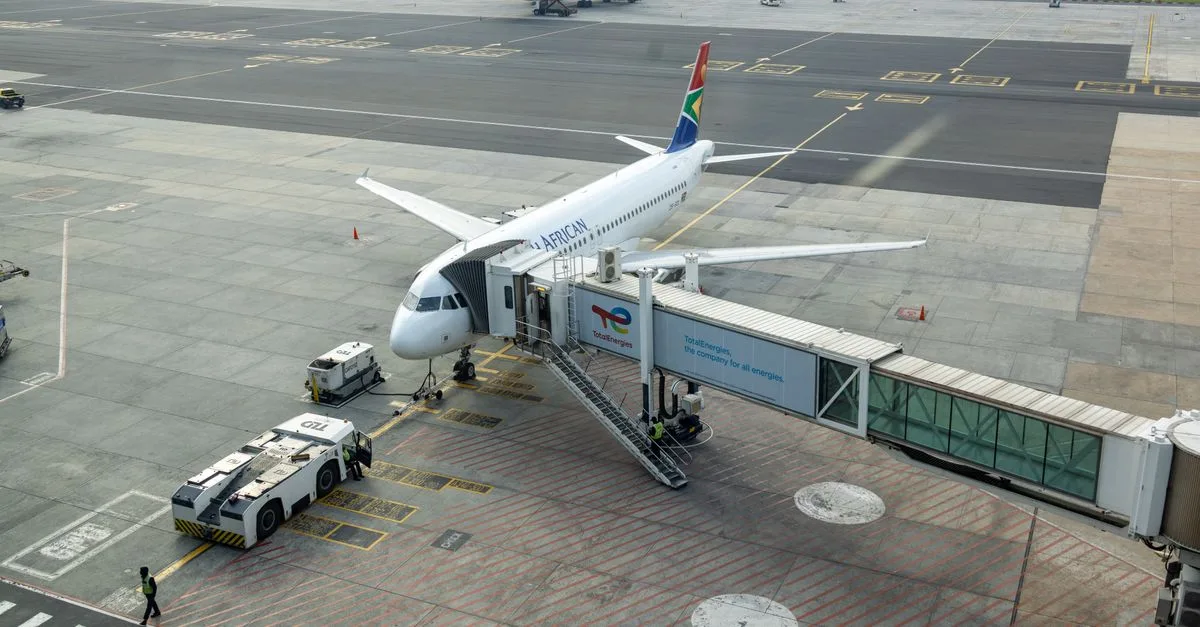 South African Airways plane docked at a gate in an airport, captured from an aerial view.