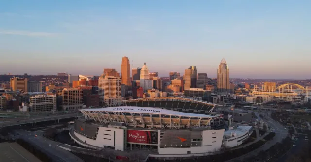 Aerial view of Cincinnati's skyline featuring Paycor Stadium during sunset, highlighting urban cityscape.