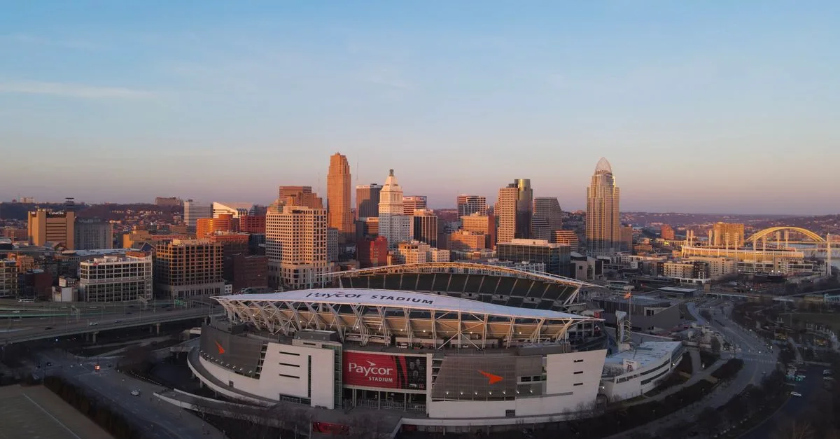 Aerial view of Cincinnati's skyline featuring Paycor Stadium during sunset, highlighting urban cityscape.