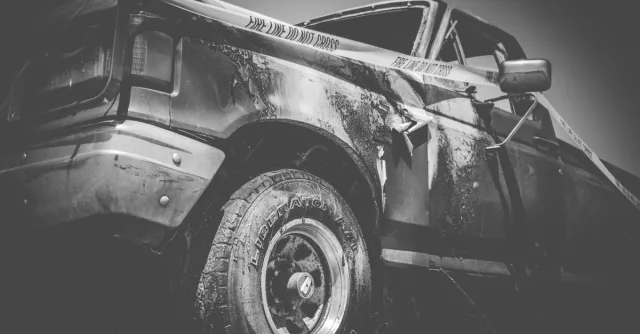 Dramatic black and white image of a damaged truck with police tape.