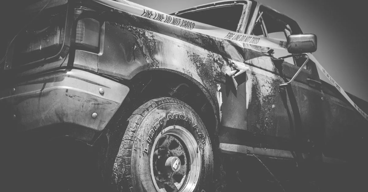 Dramatic black and white image of a damaged truck with police tape.