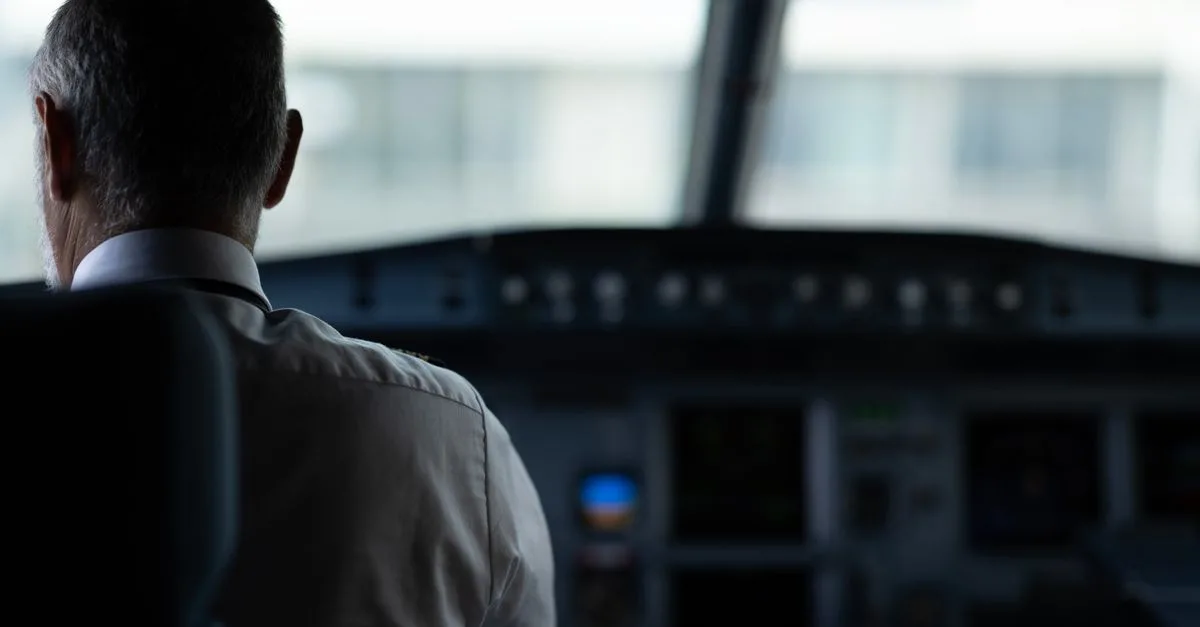 A focused view of an airline pilot in the cockpit, emphasizing responsibility and aviation control.