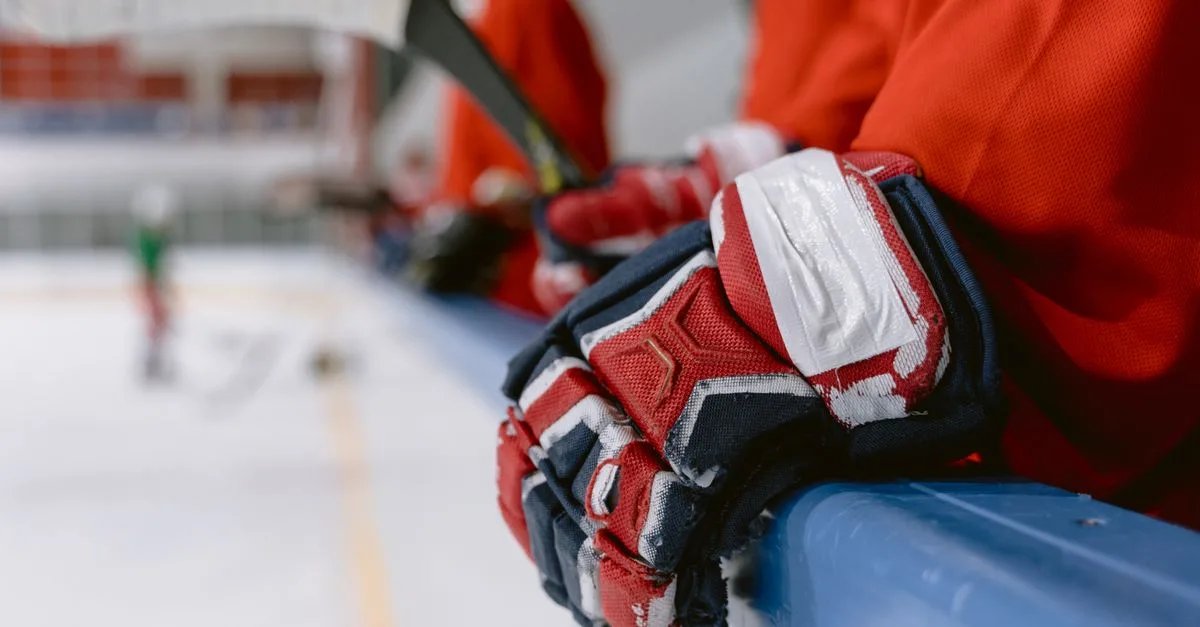 Detailed view of hockey gloves resting on a rink railing during a game pause.