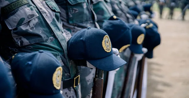 Close-up of uniformed police officers standing in formation with caps on display outdoors.