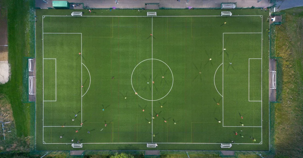 Top-down shot of a soccer match on a green field in Brighton, UK.