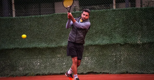 A focused male player practicing tennis on a clay court in Altinoluk, Türkiye.