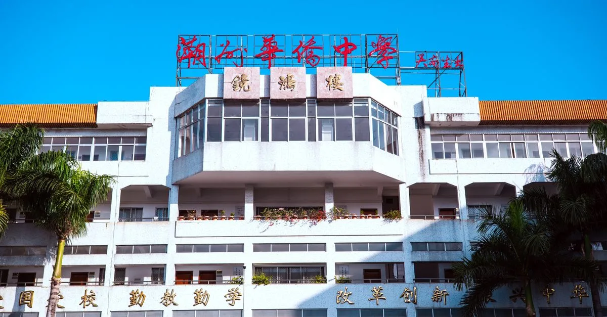 A large urban school building with palm trees and bright signage under a clear blue sky.