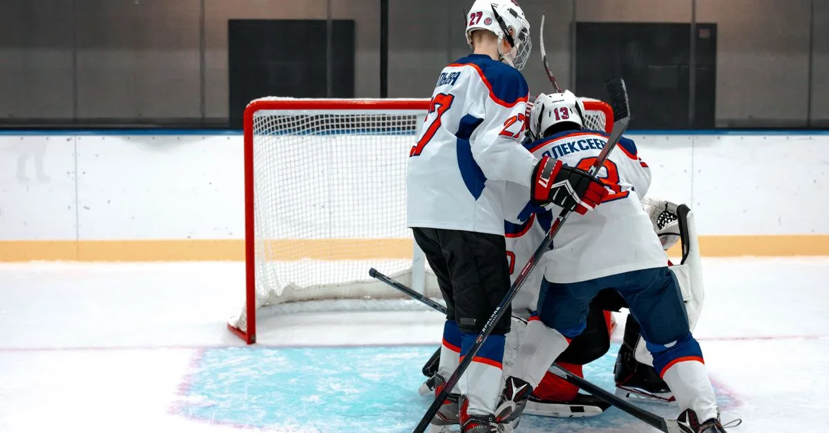 Ice hockey players compete intensely near the goal on a rink.