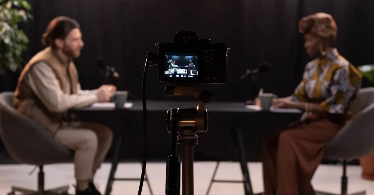 Two hosts recording a podcast in a studio setting with professional equipment.
