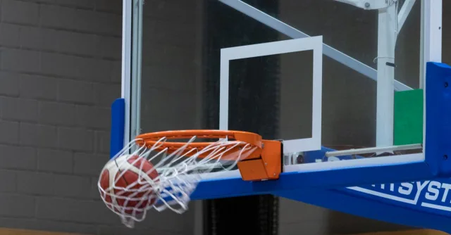 Close-up of a basketball scoring through the hoop in an indoor court setting.