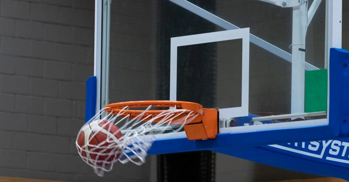 Close-up of a basketball scoring through the hoop in an indoor court setting.