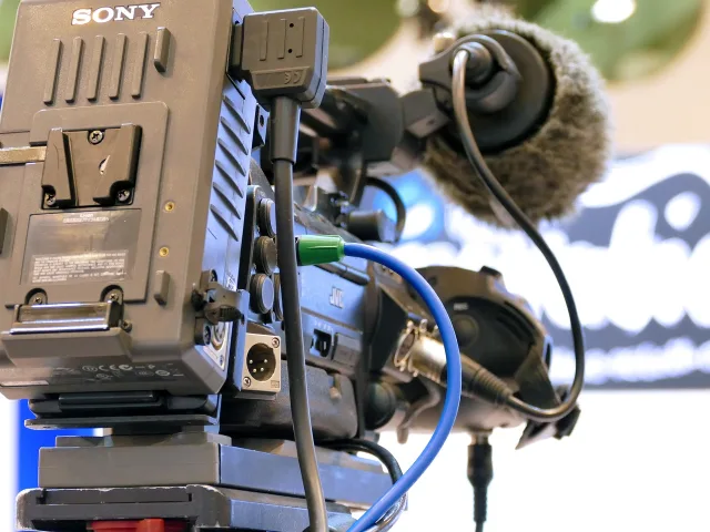 A professional studio microphone in a dimly lit broadcast setting.
