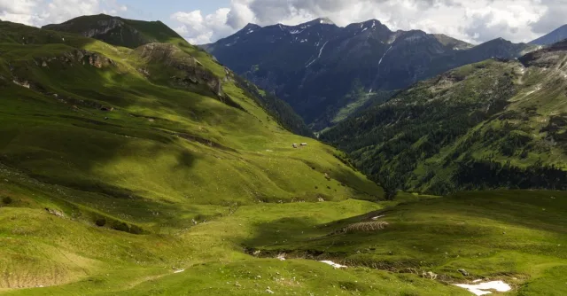 Captivating view of lush green valleys and majestic mountains under a cloudy sky.