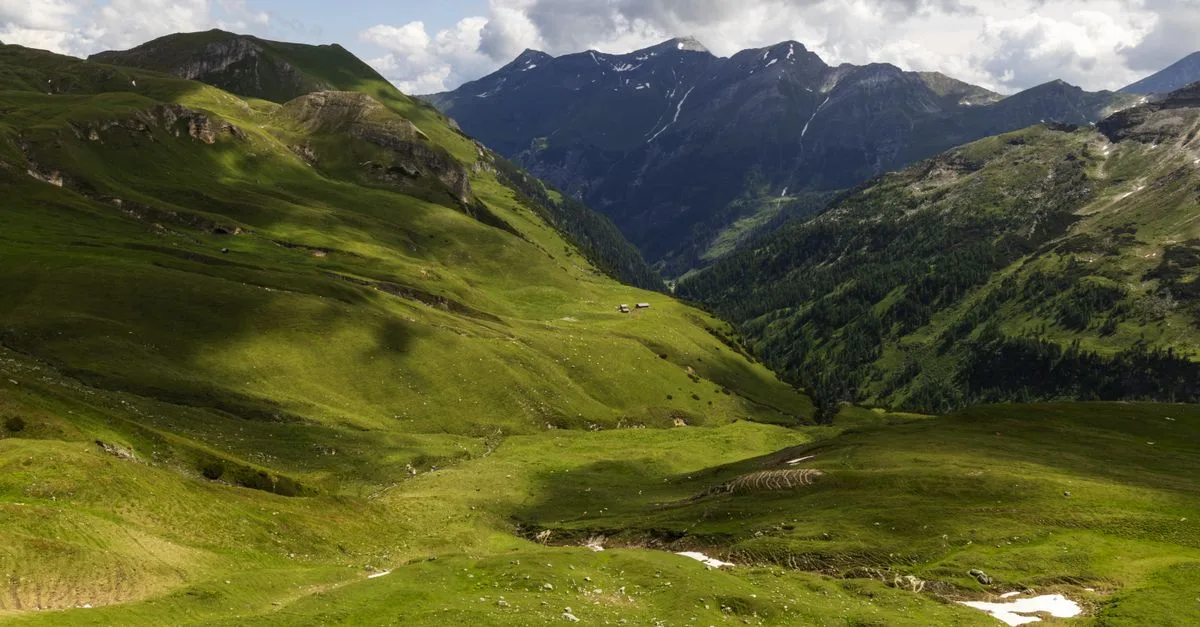 Captivating view of lush green valleys and majestic mountains under a cloudy sky.