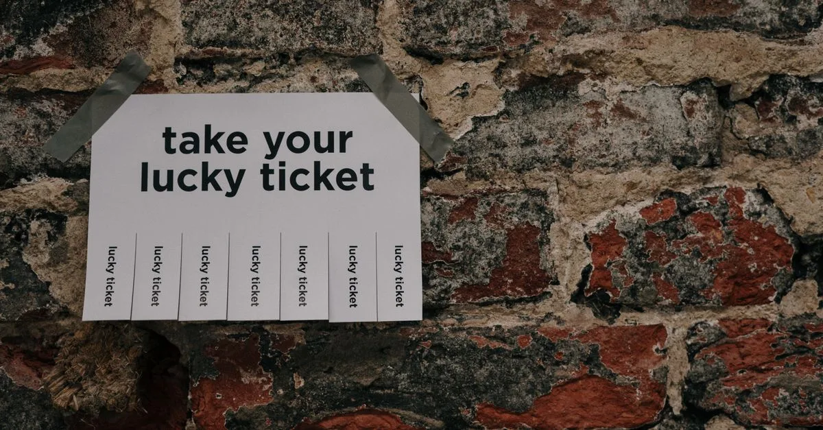 Close-up of a 'Take Your Lucky Ticket' sign taped to a rustic brick wall.