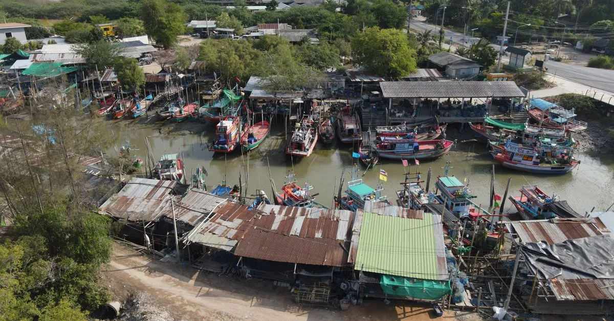 Aerial shot of colorful fishing boats docked in Nong Khanan, Thailand, showcasing village life.